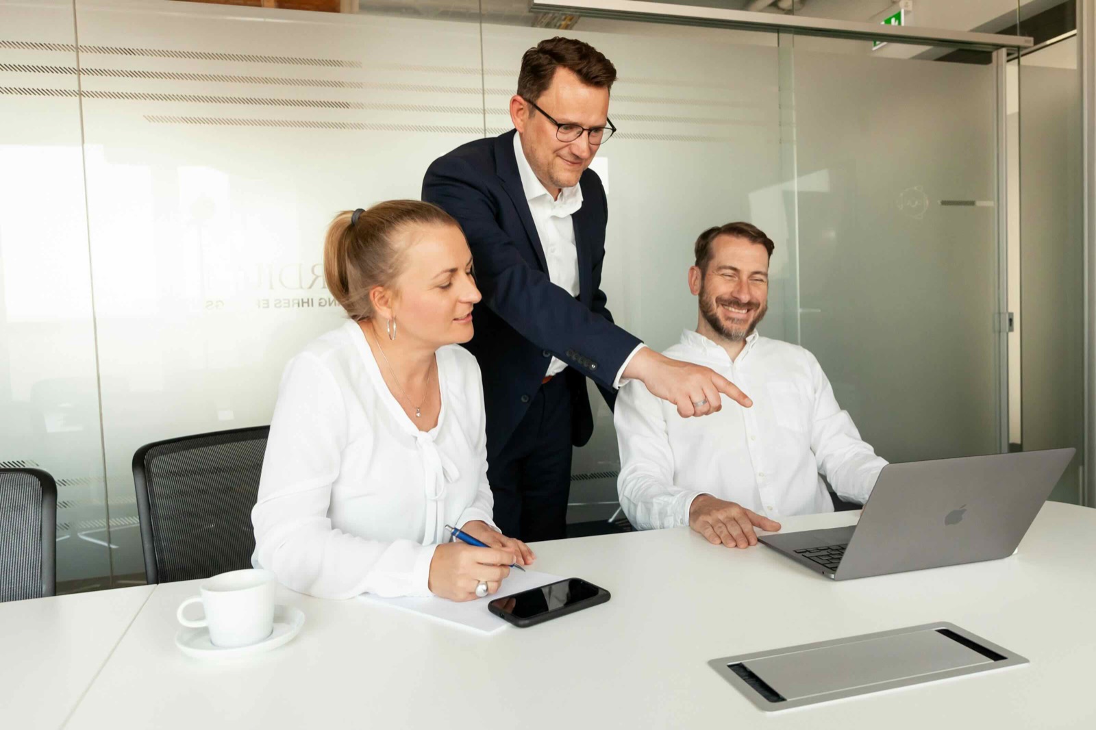 Drei Personen besprechen gemeinsam Unterlagen an einem Laptop